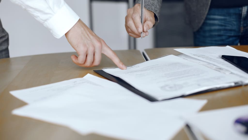 Business men sitting at the lawyers’s desk. People signing important documents.